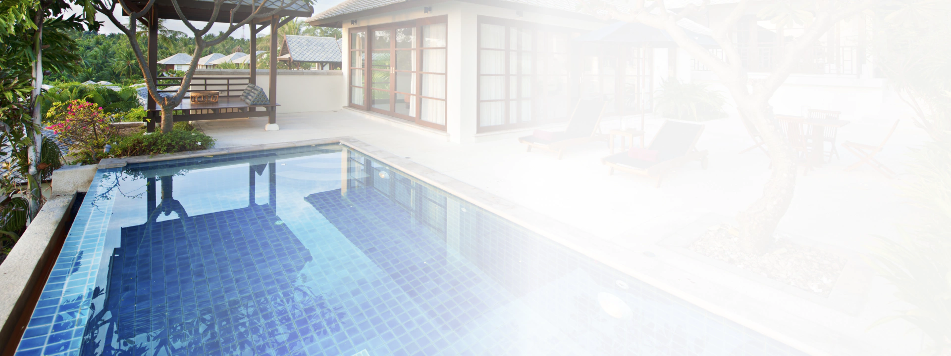 outdoor pool area with trees and sunloungers